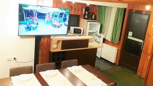 A dining area with a TV, microwave, and refrigerator. - Traveland Butique Resort Poiana Brasov (Brasov)