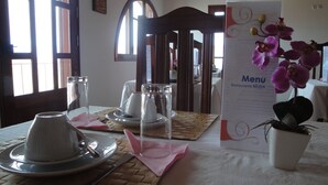 Une table à manger dressée avec des assiettes, des couverts et un présentoir à menus.