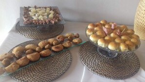 Une table de buffet où sont présentés divers produits de boulangerie, notamment des pâtisseries et des petits pains, disposés sur des sets de table en fibres tressées.