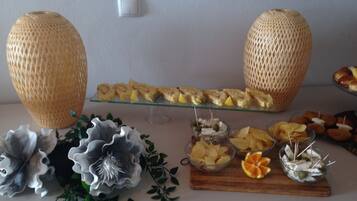 A buffet table with various food items, decorative flowers, and two large woven baskets.