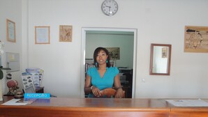Un comptoir d’accueil avec une horloge, des photos encadrées et une pancarte indiquant « RÉCEPTION ».
