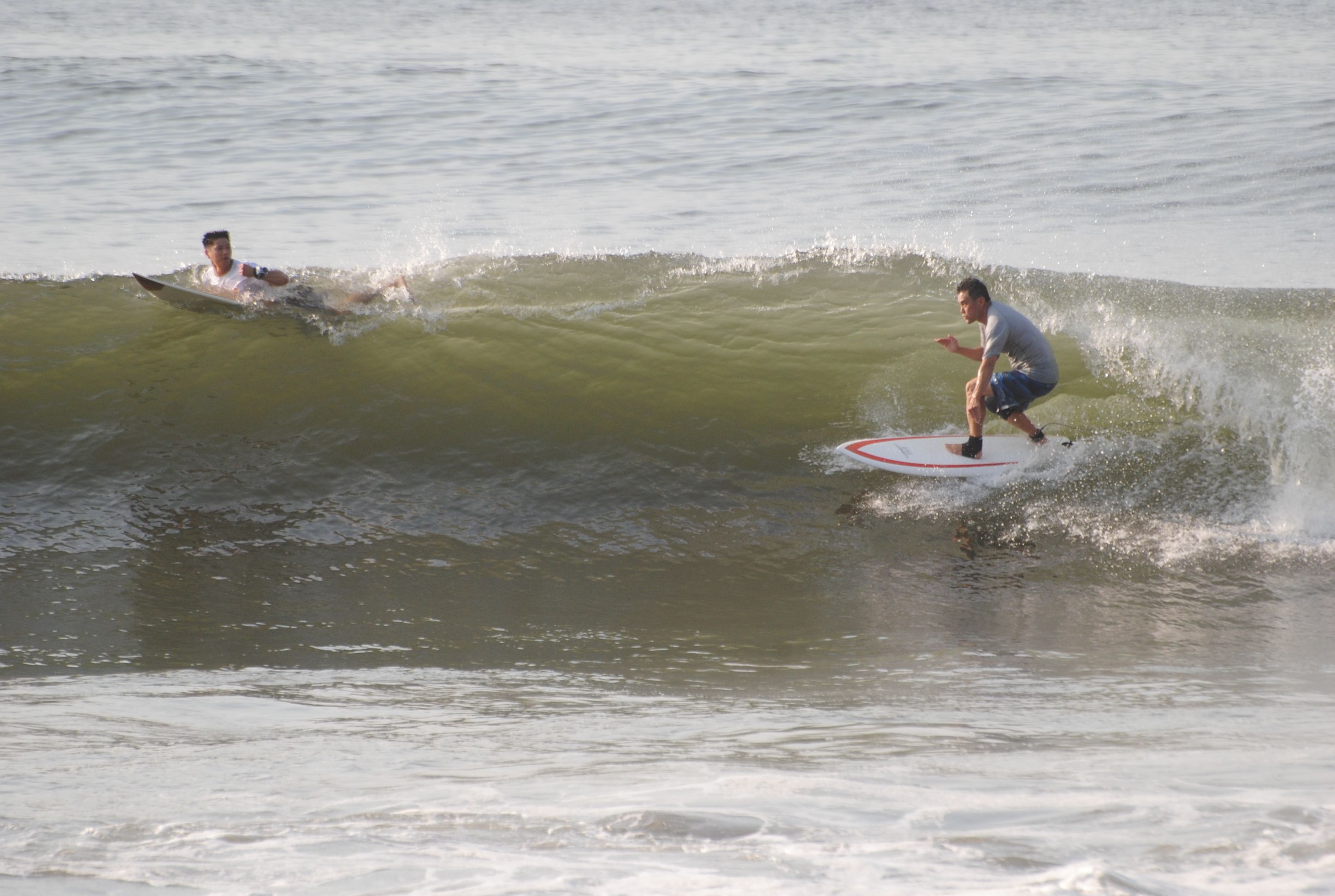 Twee surfers op een golf, met een helder uitzicht op de oceaan.