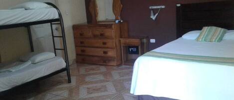 Una habitación con literas, un aparador de madera, un espejo y una cama con almohada a rayas.