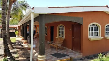A two-story building with a covered porch, palm trees, and a tiled patio.