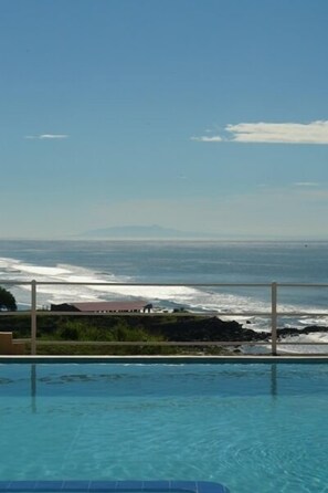 An infinity pool with a view of the ocean and distant mountains.