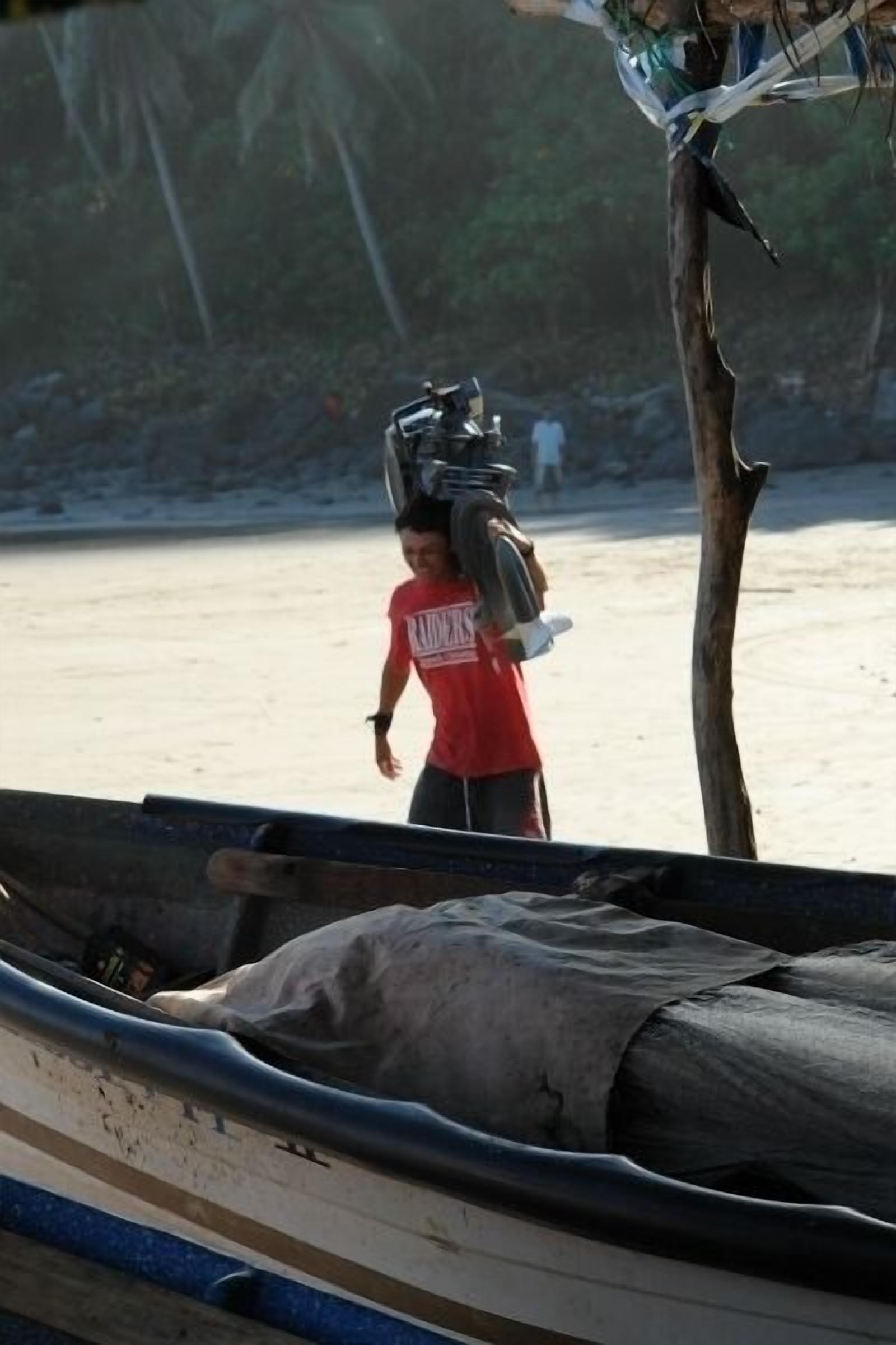 A boat with a person carrying a large object on their head.