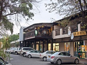 A street view with parked cars, a building with an 'AIR & BEAUTY' sign, and a balcony with a person visible.