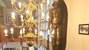 A grand chandelier in a spacious room with a wooden staircase and a large decorative shield on the wall. - Digger Inn (Francistown)