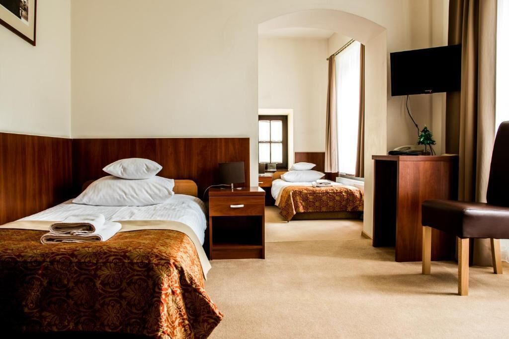 Une chambre d’hôtel avec deux lits, une télévision, un bureau et une chaise.