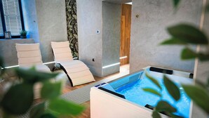 A modern spa room with a hot tub, two lounge chairs, and a wooden door. - Dom Na Podwalu Lublin  (Lublin)