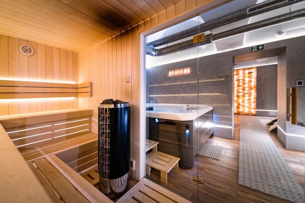 A modern sauna with wooden benches, a glass partition, and a visible steam room.
