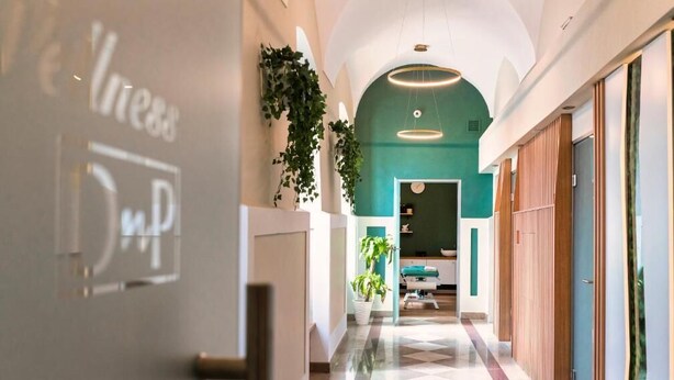 A hotel corridor with a check-in desk, a teal wall, and a modern light fixture. - Dom Na Podwalu Lublin  (Lublin)