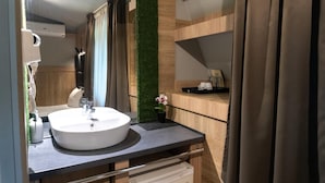 A modern bathroom with a round sink, a mirror, and a green vertical garden. - Hotel Allur (Plovdiv)