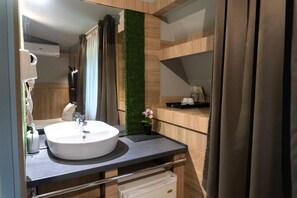 A modern bathroom with a round sink, a mirror, and a green vertical garden. - Hotel Allur (Plovdiv)