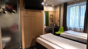 A hotel room with a bed, a desk, a chair, a TV, and a window with curtains. - Hotel Allur (Plovdiv)