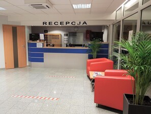 A reception area with a counter, seating, and a potted plant. - Hotel Olivia (Gdańsk)
