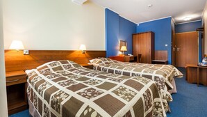 A hotel room with two beds, a desk, a wardrobe, and a bathroom. - Hotel Olivia (Gdańsk)