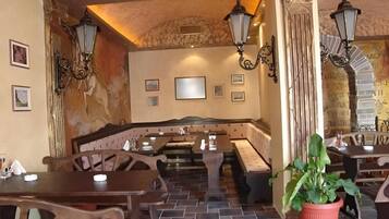A restaurant interior with booths, tables, and wall-mounted lights.