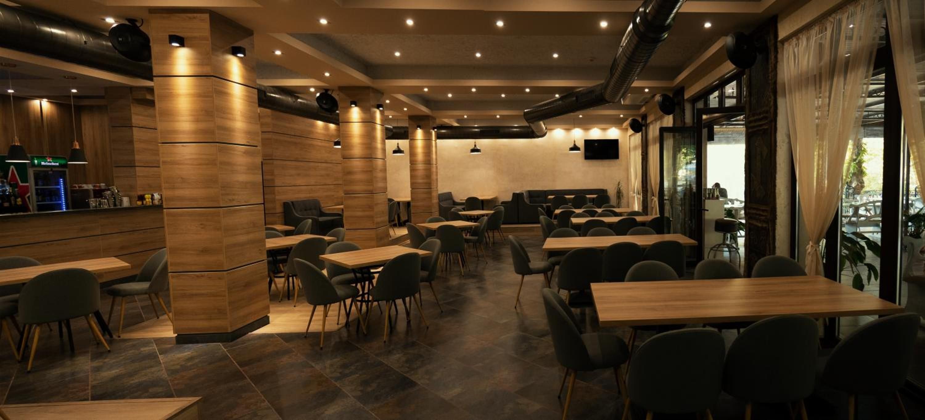 En modern restaurang med träpanel på väggarna, flera sittgrupper och en bardisk.