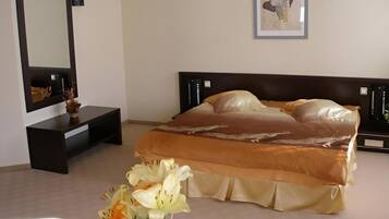 A bedroom with a bed, bedside table, mirror, and a framed picture on the wall.