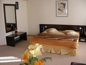Un dormitorio con cama, mesita de noche, espejo y un cuadro en la pared.