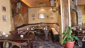 Interior de restaurante con cabinas, mesas y luces en la pared.