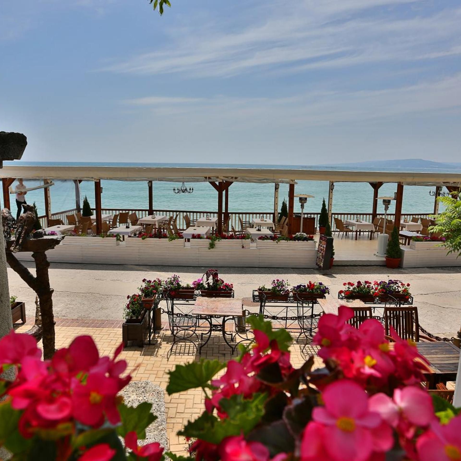 An outdoor seating area with tables and chairs, overlooking a body of water.