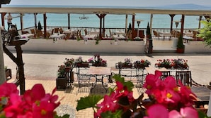 An outdoor seating area with tables and chairs, overlooking a body of water.