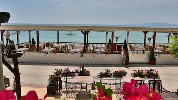 An outdoor seating area with tables and chairs, overlooking a body of water.