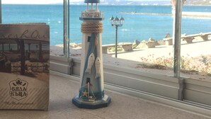 A coastal view with a lighthouse model, a palm tree, and a beach in the background.