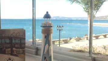 A coastal view with a lighthouse model, a palm tree, and a beach in the background.
