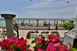 An outdoor seating area with tables and chairs, overlooking a body of water. - Hotel White House (Borovets)