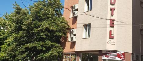Um edifício de hotel com um letreiro grande escrito 'HOTEL', diversas janelas e sacadas com plantas.