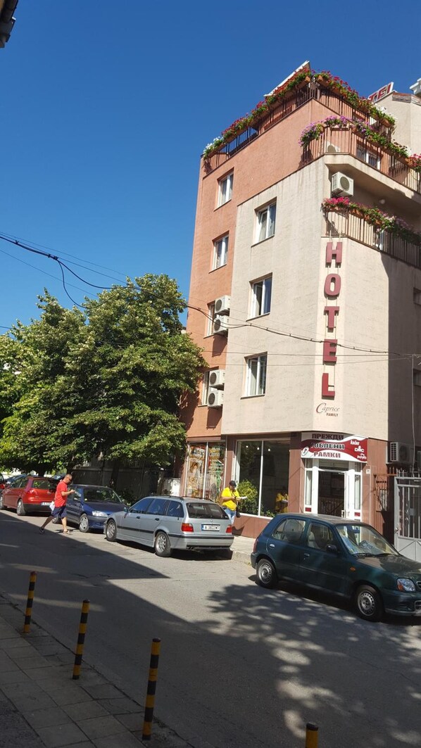 A hotel building with a prominent 'HOTEL' sign, multiple windows, and balconies with plants.