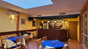 Un ristorante con zona bar, tavoli con tovaglie blu e un lucernario.