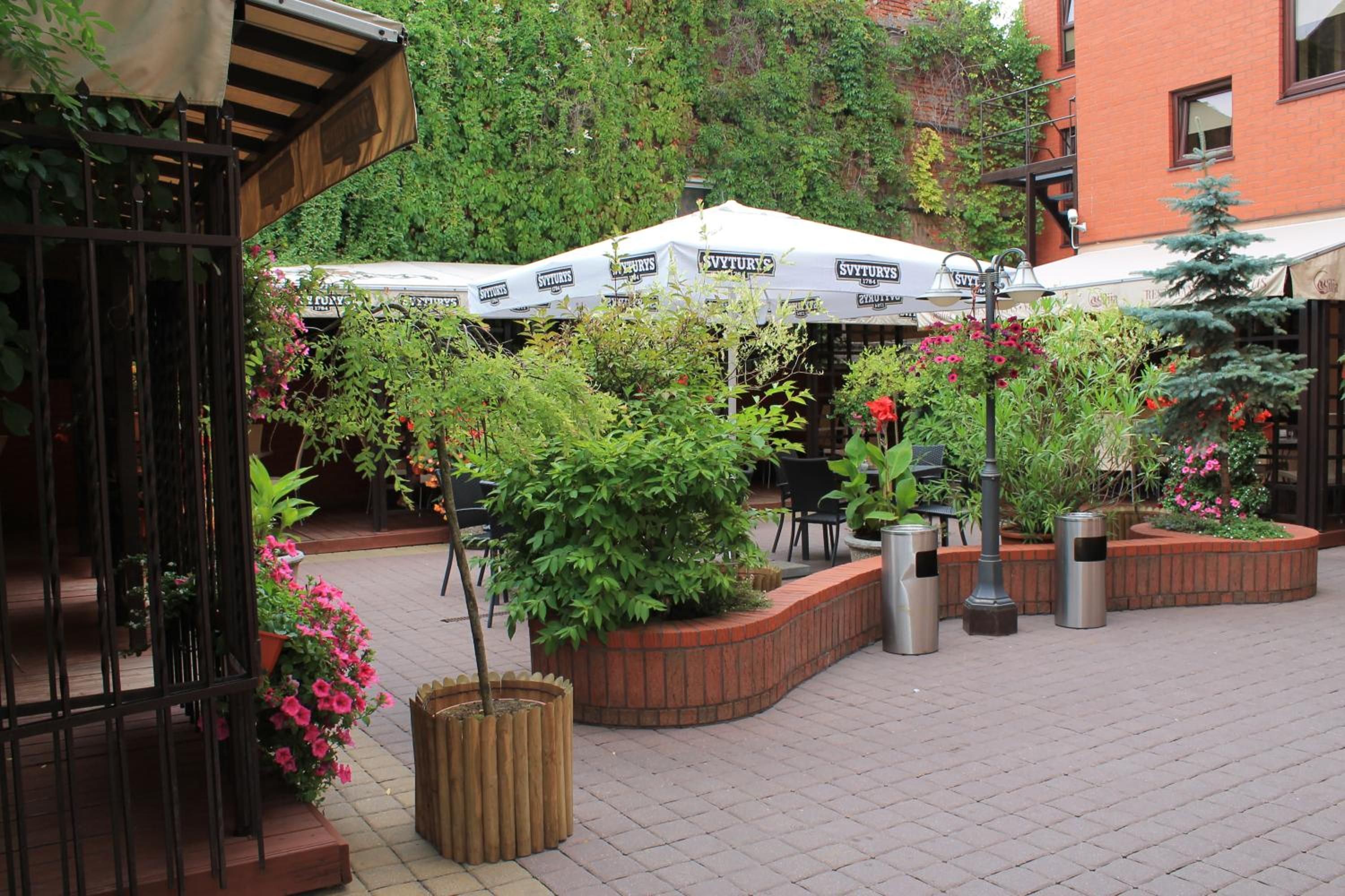 An outdoor cafe area with tables, chairs, and umbrellas.