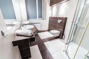 A modern bathroom with a shower, toilet, and sink.