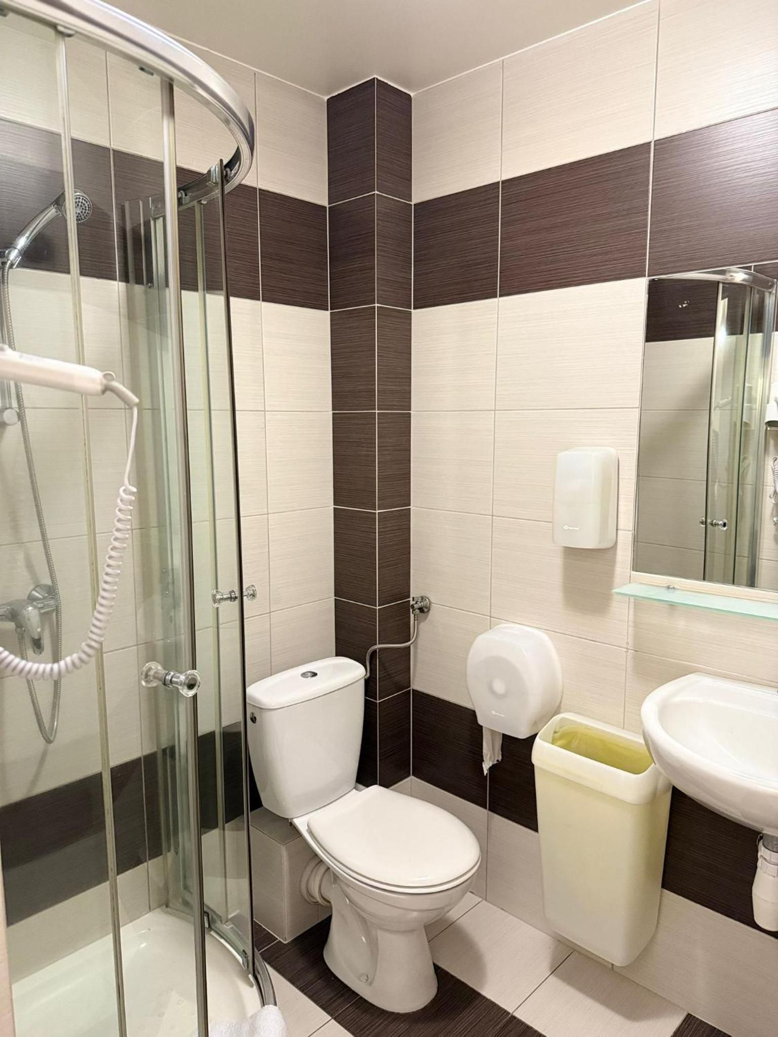A bathroom with a glass-enclosed shower, a toilet, a bidet, and a sink with a mirror.