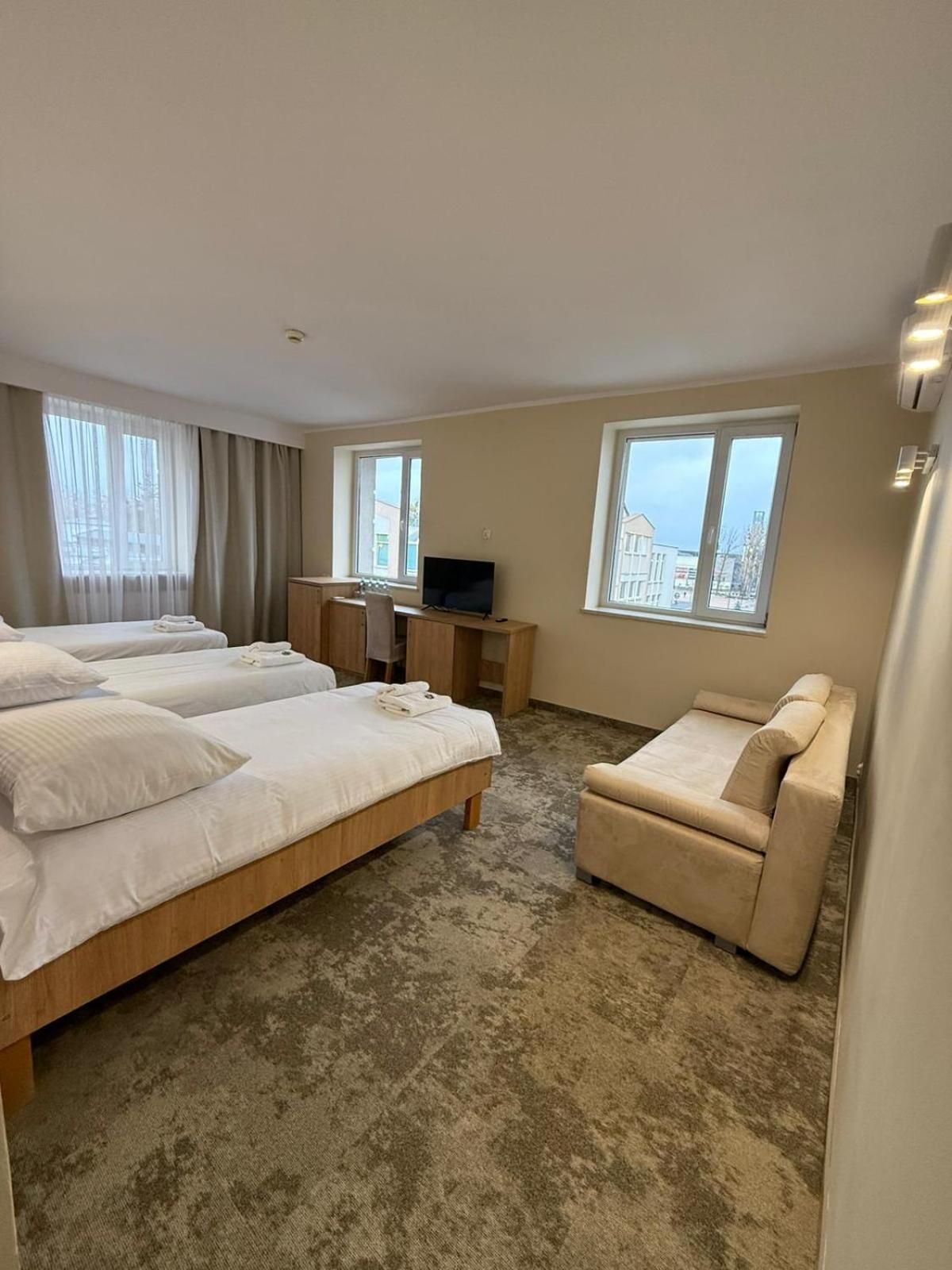 A hotel room with a bed, a desk, a chair, and a sofa.