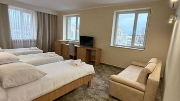 A hotel room with a bed, a desk, a chair, and a sofa.