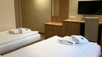 A hotel room with two beds, a desk, a flat-screen TV, and a mirror.