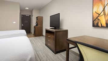Une chambre d’hôtel avec deux lits, un bureau, une télévision et un tableau au mur.