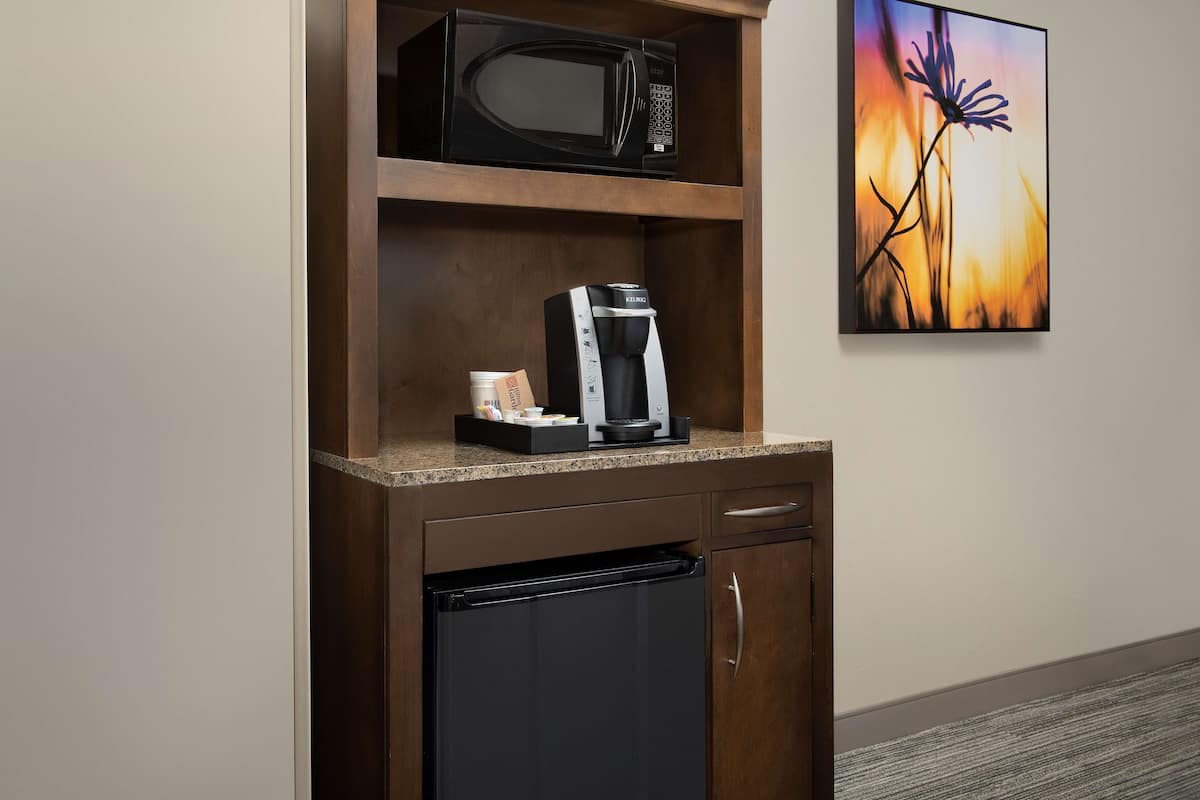 A kitchenette with a microwave, coffee maker, and refrigerator.