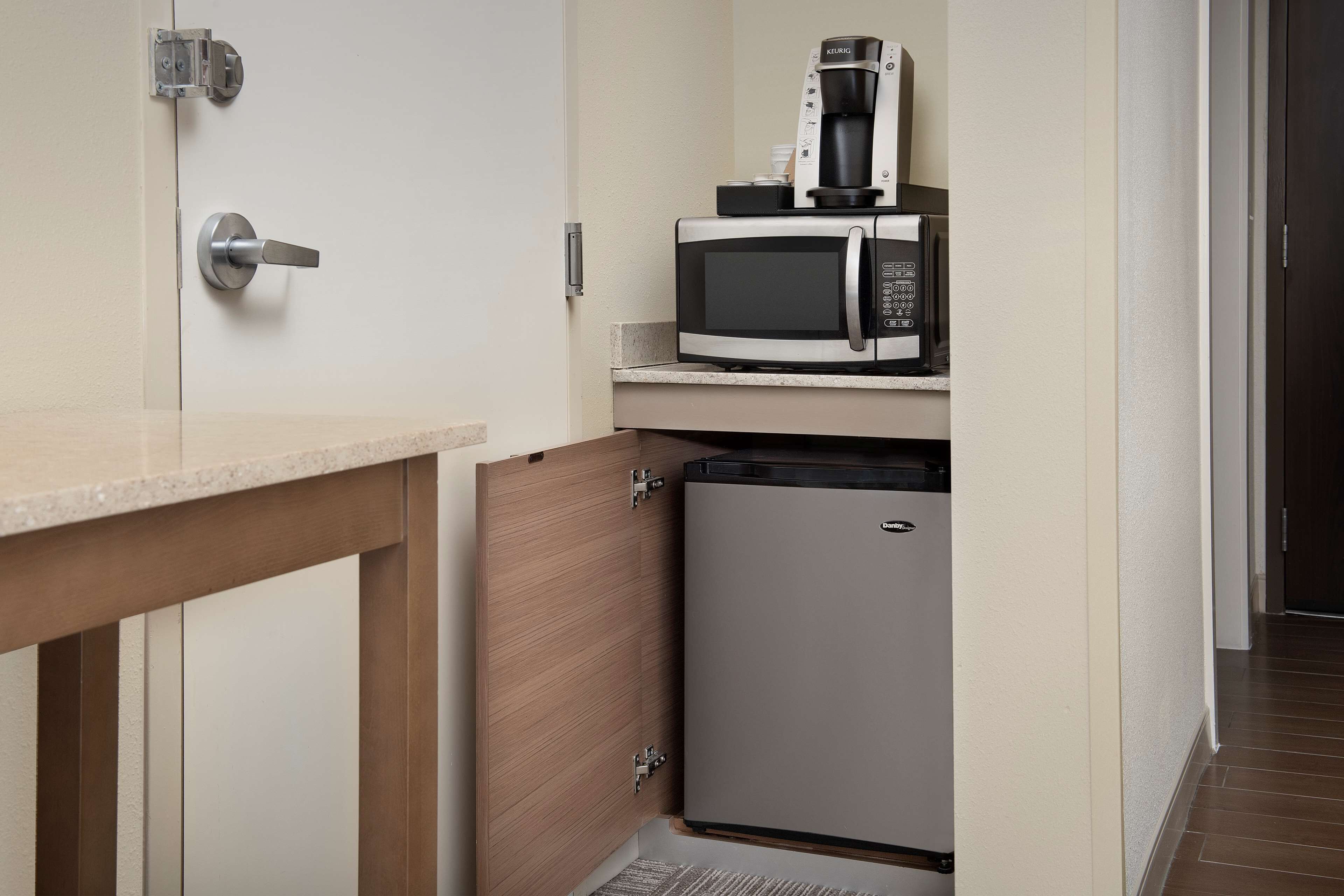 A compact kitchenette with a microwave, coffee maker, and a small refrigerator.