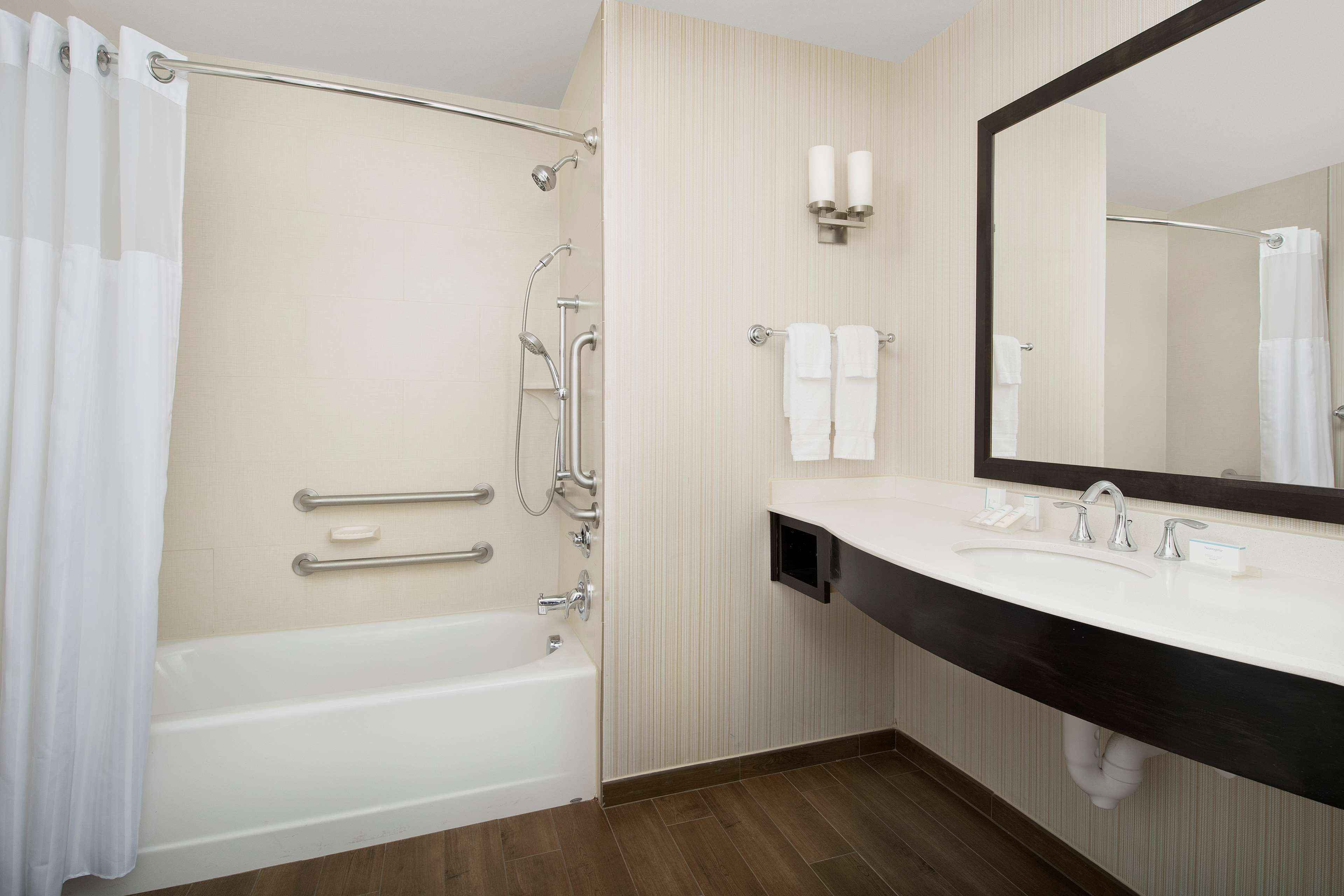 A modern bathroom with a bathtub, shower, and vanity with a large mirror.