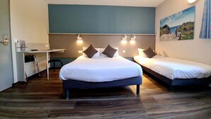 A hotel room with two beds, a desk, and a chair.