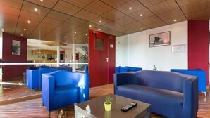 A modern lobby with blue seating, a wooden floor, and a staircase.