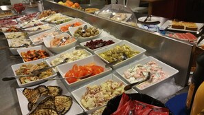 A buffet with various food options including salads, grilled vegetables, and seafood.