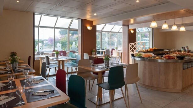 A modern restaurant with a central bar, multiple dining tables, and chairs.
