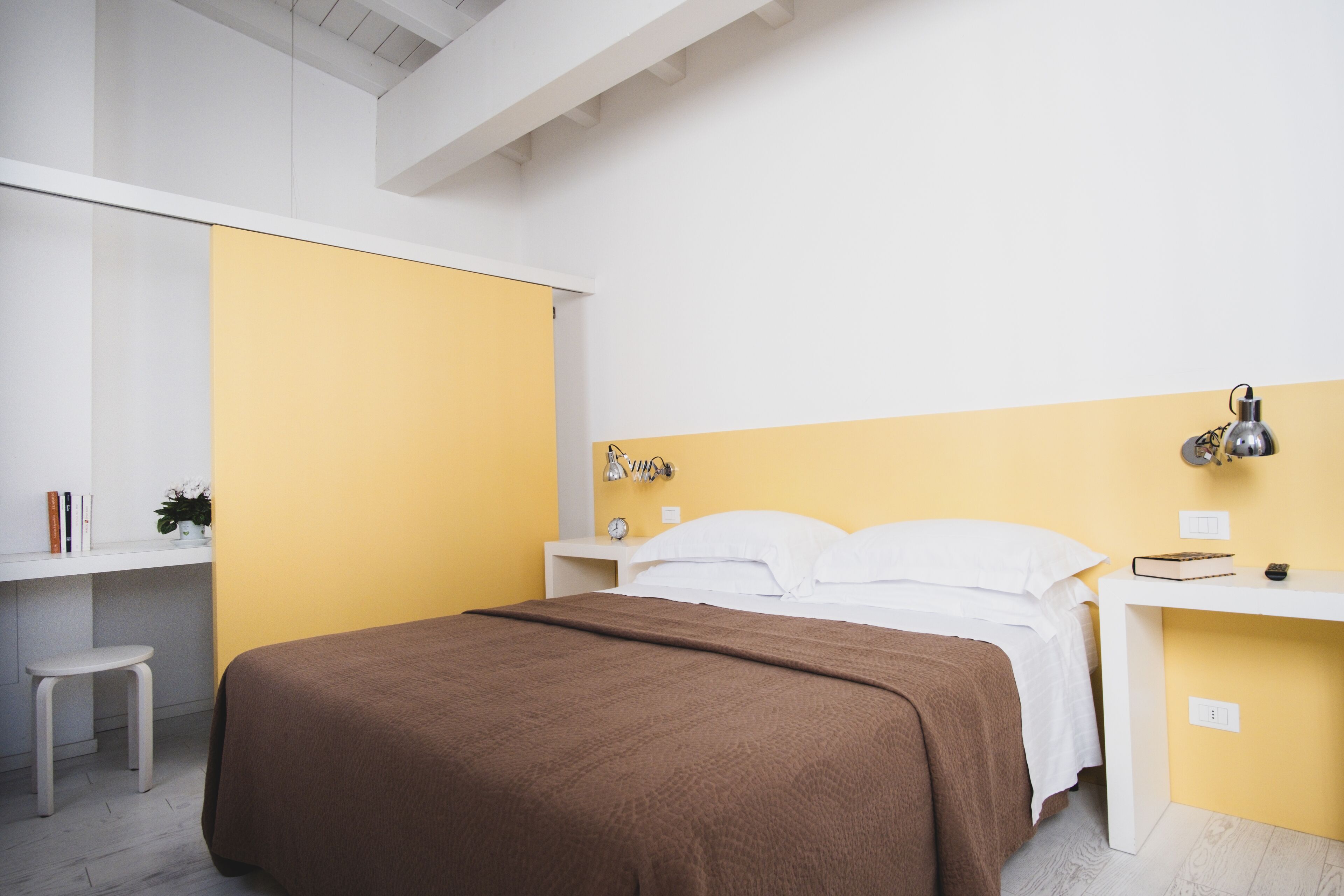 A bedroom with a bed, bedside tables, a desk, and a chair.